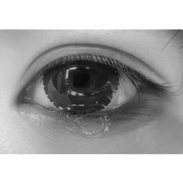 一张在流泪的眼睛的特写图片,瞳孔里面是两个人的背影
