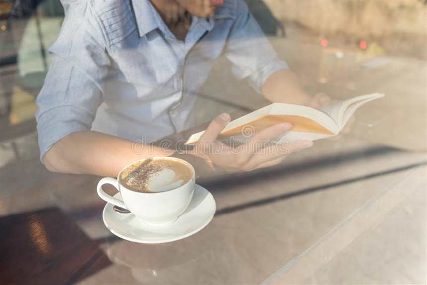 与一个杯子的看书热奶咖啡.