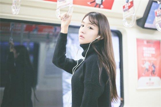 地铁上带耳机听音乐的孤单女生