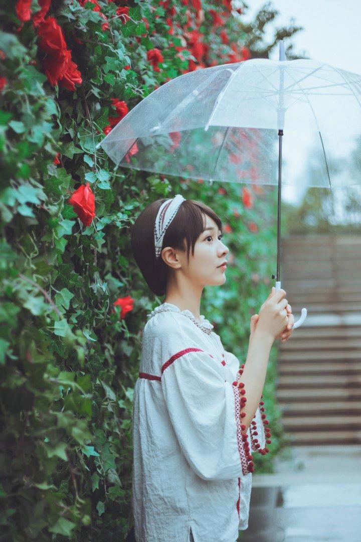 在花园中手撑雨伞的短发美女